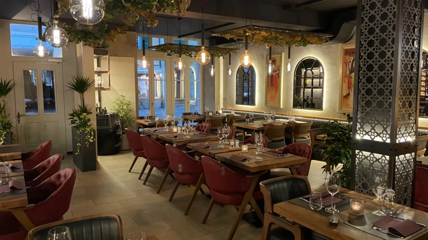 Stimmungsvoller Gastraum des Ristorante La Dolce Vita in Bremgarten mit warmen Hängeleuchten, Holztischen und weinroten Sesseln am Abend.