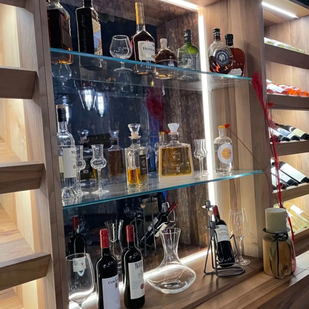 Italienische Weine und Grappasorten im beleuchteten Holzregal der Bar.