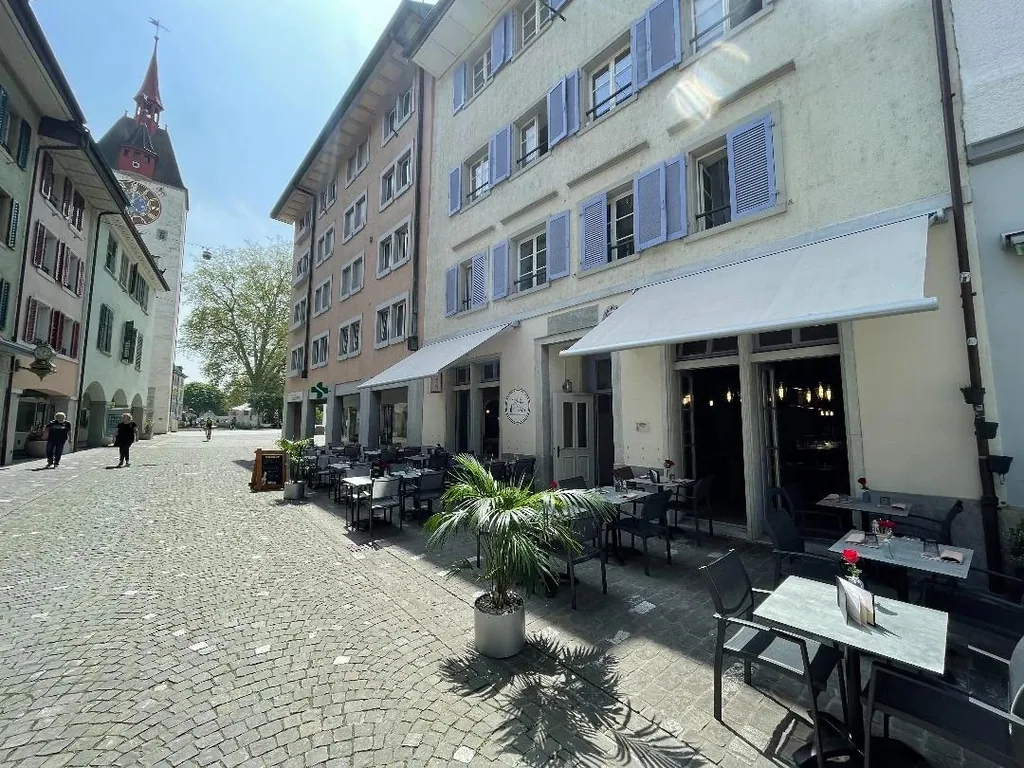 Blick durch die Bremgarter Altstadt mit Aussentischen und dem historischen Spittelturm im Hintergrund.